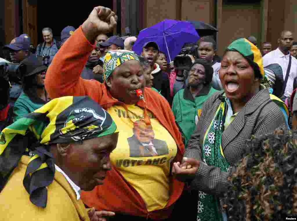 Para anggota Liga Kongres Wanita Afrika Nasional bernyanyi di depan pengadilan sebelum pengadilan atlet bintang track Olimpiade dan Paralimpiade Oscar Pistorius di Pretoria. 
