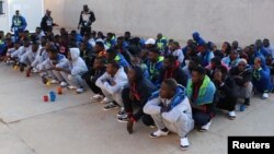 FILE - Migrants wait before being deported by Libyan authorities, in Misrata, Libya, Feb. 19, 2018.