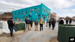 FILE - Jay Inslee, center, governor of the U.S. state of Washington and 2020 Democratic presidential candidate tours flood damage, in Hamburg, Iowa, April 12, 2019. 