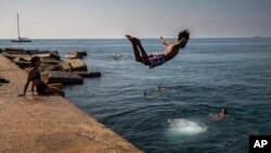 Seorang bocah laki-laki menerjunkan diri ke air di pantai Barcelona, Spanyol, 25 Juli 2019. 