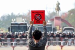 Un manifestante sostiene una pancarta frente a una línea policial mientras protesta contra el golpe, en Naipyidó, capital de Myanmar.