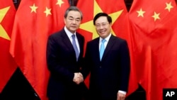 Chinese Foreign Minister Wang Yi, left and Vietnamese Foreign Minister Pham Binh Minh shake hands in Hanoi, Vietnam, April 1, 2018.