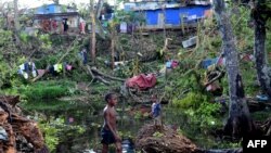 Children play in water amongst the debris of fallen trees just outside Vanuatu's capital, Port Vila, after Cyclone Pam ripped through the island nation, March 17, 2015.