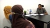 “Noradhiah” and “Shahirah” listen and watch the Muslim Consumer Association Malaysia hold a phone call to start a negotiation with a loan shark’s henchman. (Dave Grunebaum/VOA)