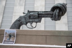 A photo of a Syrian child is placed next to "Non-Violence" by Swedish artist Carl Fredrik Reutersward, after a moment of silence was observed, March 15, 2017 at United Nations headquarters in New York to mark the 6th anniversary of the Syrian conflict.