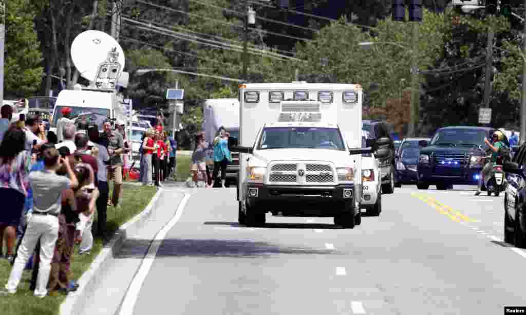 An ambulance carrying the American missionary Nancy Writebol, who was infected with Ebola in West Africa, drives past crowds of people, at Emory University Hospital, in Atlanta, Georgia Aug. 5, 2014.