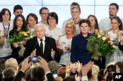 Conservative Law and Justice leader Jaroslaw Kaczynski, center left, along with Justice candidate for Prime Minister Beata Szydlo, center right, delivers a speech at the party's headquarters in Warsaw, Poland, Oct. 25, 2015.