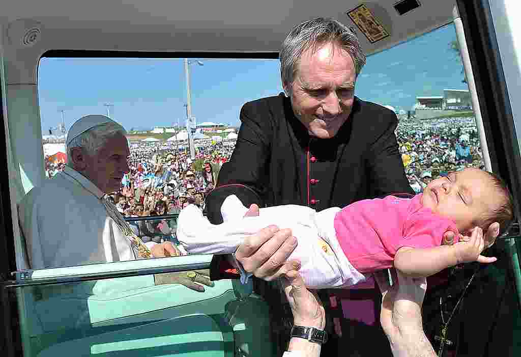 Monseñor Georg Gaenswein, sostiene un bebé que recibió la bendición papal en el papamóvil en el Parque del Bicentenario, en México. (AP)