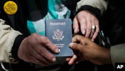 File - Outside a Department of State office, a World War II veteran hold his U.S. passport, June 2, 2014.