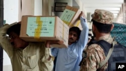 FILE - Pakistan's Election Commission staff carry election material to arrange it for upcoming general election at an office in Lahore, Pakistan, July 21, 2018. 