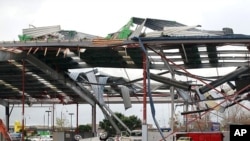 A car in a mall parking garage is overturned in front of a large building after a tornado ripped through the suburb of Albany in Auckland May 3, 2011.