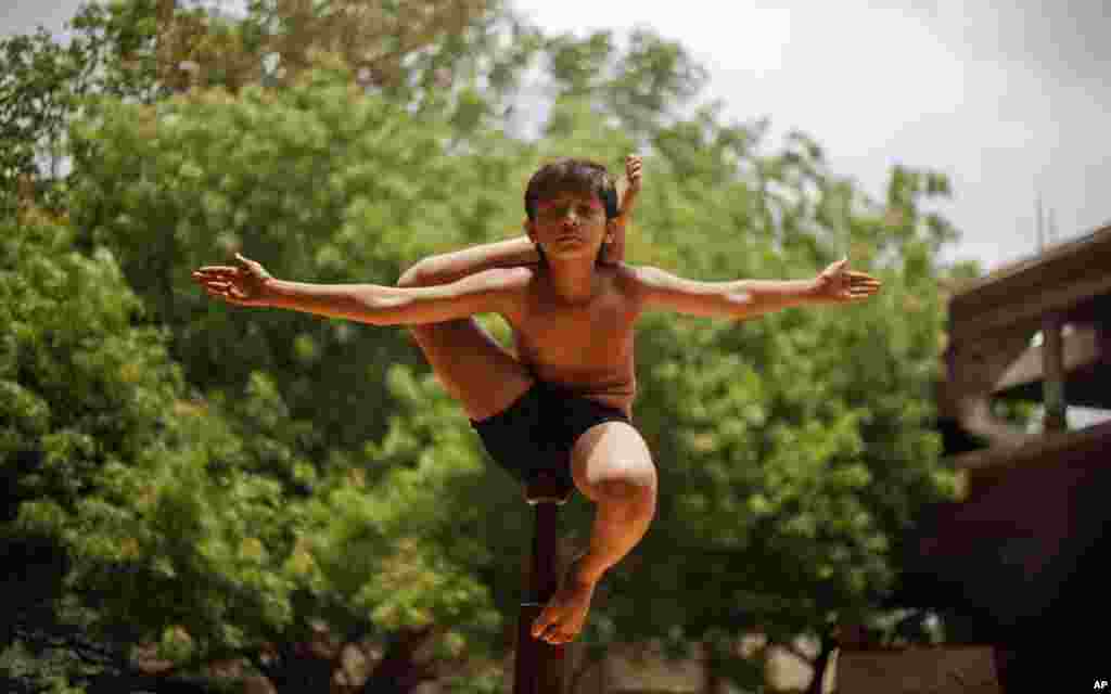 인도 아흐마다바드에서 한 소년이 나무 장대 위에 올라 전통적인 균형잡기 놀이를 하고 있다.