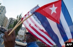A man waves the US and Cuban flags as he walks in front of the new Cuban Embassy shortly before it's official ceremonial opening July 20, 2015, in Washington, D.C.