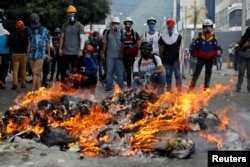 Opposition supporters stand in front of a fire during clashes with riot police at a rally against President Nicolas Maduro in Caracas, Venezuela, May 3, 2017.