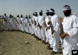 FILE - Taliban suicide bombers stand guard during a gathering of a breakaway Taliban faction, in the border area of Zabul province, Afghanistan.
