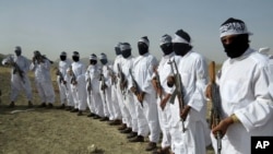 FILE - Taliban suicide bombers stand guard during a gathering of a breakaway Taliban faction, in the border area of Zabul province, Afghanistan. Eighteen bombers in training were killed in a recent airstrike in the province, Afghan officials say. 