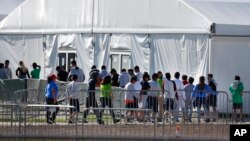 ARCHIVO - Esta foto de archivo del 19 de febrero del 2019 muestra niños entrando en fila al centro de detención Albergue Temporal Homestead para Niños no Acompañados, en Homestead, Florida. (AP Foto/Wilfredo Lee, Archivo)