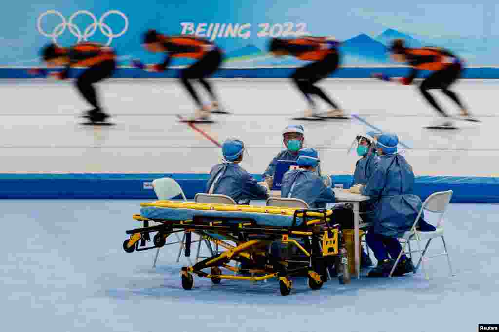 Medical staff in personal protective equipment keep watch at a speed skating training session for the Beijing 2022 Winter Olympics in Beijing, China.