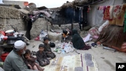 Yousuf, yang melarikan diri bersama keluarganya dari rumahnya di Afghanistan timur delapan tahun lalu untuk menghindari perang, duduk bersama anak-anak sementara istrinya membakar plastik saat dia membuat teh, di Kabul, Afghanistan. (Foto: AP//Rahmat Gul)