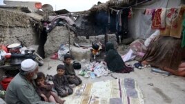 In this Oct. 29, 2019 photo, Yousuf, who fled with his family from his home in eastern Afghanistan eight years ago to escape the war, sits with children while his wife burns plastic as she makes tea, in Kabul, Afghanistan. (AP Photo/Rahmat Gul)