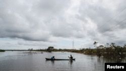 Hombres indígenas miskitos usan un bote para cruzar una carretera inundada por el río Wawa Boom debido a las fuertes lluvias causadas por el huracán Iota a su paso por la costa caribeña en Bilwi en 2020.