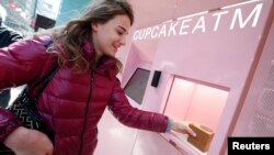 Seorang perempuan mengambil cupcake marshmallow coklat dari Cupcake ATM di Sprinkles Cupcake Bakery di Manhattan, New York City (26/3). (Reuters/Mike Segar)