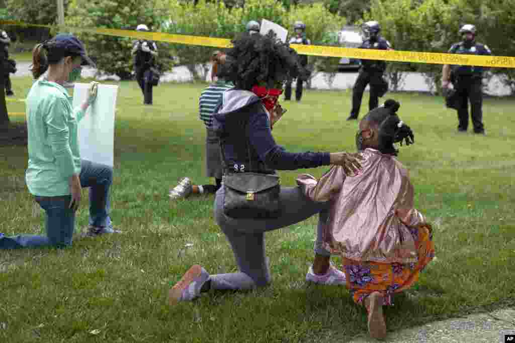 Ericka Ward-Audena, of Washington, puts her hand on her daughter Elle Ward-Audena, 7, as they take a knee in front of a police line during a protest of President Donald Trump&#39;s visit to the Saint John Paul II National Shrine, Tuesday, June 2, 2020, in Washington. &quot;I wanted my daughter to see the protests, Ward-Audena said. (AP Photo/Jacquelyn Martin)