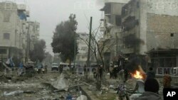 In this photo provided on Jan. 3, 2018 by the Syrian anti-government activist group, Edlib Media Center, EMC, which has been authenticated based on its contents and other AP reporting, shows members of the Syrian civil defense known as the White Helmets, gathering at a street which was attacked by Russian airstrikes, in Maarat al-Nuaman town, southern Idlib province. 