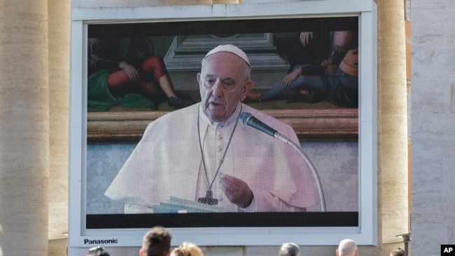 Los fieles miran al Papa Francisco pronunciar la oración del Ángelus en una pantalla gigante, en la Plaza de San Pedro, en el Vaticano, el domingo 8 de marzo de 2020.