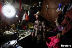 Migrant worker Wang Qin and her 10-year-old granddaughter Feng Aobin sit in their one-room home at the outskirts of Beijing, Oct. 1, 2017.