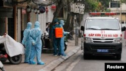 Một nhân viên y tế khử trùng xe cứu thương gần nhà của một bệnh nhân bị nhiễm virus corona tại một khu phố bị cách li ở Hà Nội, ngày 7 tháng 3, 2020.