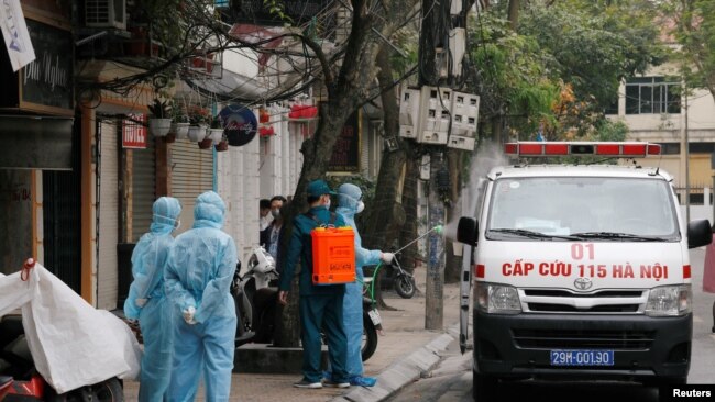 A health worker disinfects an ambulance near the house of a corona virus infected patient at a quarantined street in Hanoi, Vietnam March 7, 2020. REUTERS/Kham - RC2XEF90L2YK