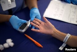 A person receives a test for diabetes during Care Harbor L.A. free medical clinic in Los Angeles, Sept. 11, 2014.