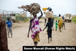 FILE - Women and children venture outside the UNMISS camp near Bentiu, in South Sudan, to collect firewood and charcoal.