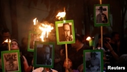 FILE - Journalists and demonstrators hold up pictures of slain journalist Javier Valdez at the Interior Ministry building in Mexico City, Mexico, May 16, 2017. 