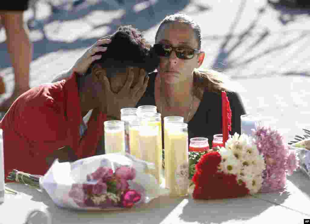 Pamela Tilton, right, comforts Che James-Riley, 18, as they light a candle at a memorial for the victims of the shooting at Marjory Stoneman Douglas High School, Feb. 15, 2018, in Parkland, Florida.