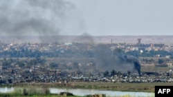 FILE - Smoke rises from the Islamic State (IS) group's last remaining position in the village of Baghuz during battles with the Syrian Democratic Forces (SDF), in the countryside of the eastern Syrian province of Deir el-Zour, March 20, 2019.
