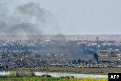 Smoke rises from the Islamic State (IS) group's last remaining position in the village of Baghuz during battles with the Syrian Democratic Forces (SDF), in the countryside of the eastern Syrian province of Deir el-Zour, March 20, 2019.