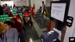 Patients wait near a queue number dispenser affected by "WannaCry" attack at Dharmais Cancer Hospital in Jakarta, Indonesia, May 15, 2017. (AP Photo/Dita Alangkara)