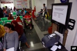 FILE - Patients wait near a queue number dispenser affected by WannaCry attack at Dharmais Cancer Hospital in Jakarta, Indonesia, May 15, 2017.