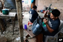 Electronics repairman Santo Francisco Acosta fixes a stereo on his porch in San Pedro Sula, Honduras, Tuesday, April 30, 2019. The U.S. government has threatened Honduras and other Northern Triangle countries with security and humanitarian aid cuts.