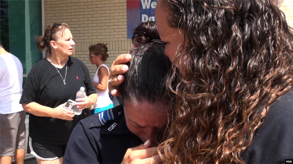 Woman comforts officer in front of Dallas Police Department headquarters, Dallas, Texas, July 10, 2016. (Photo: M. O'Sullivan/VOA)