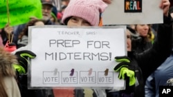 A woman holds a sign promoting voting in the upcoming midterm elections during a Women's March in Seattle, Jan. 20, 2018.