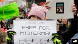 FILE - A woman holds a sign promoting voting in the upcoming midterm elections during a Women's March in Seattle, Jan. 20, 2018.
