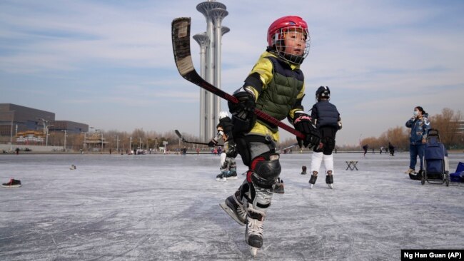 A child plays ice hockey near the Beijing Olympics Tower in Beijing, China January 18, 2022. (AP Photo/Ng Han Guan)