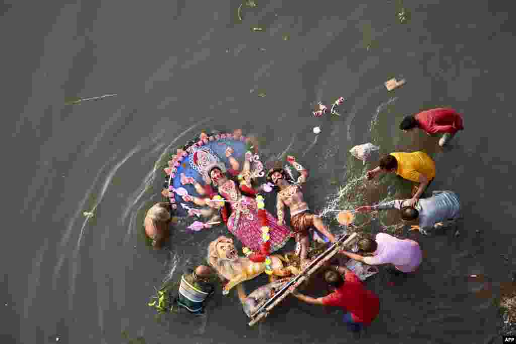 Hindu devotees immerse a clay idol of the Hindu Goddess Durga in the Buriganga River on the final day of the Durga Puja festival in Dhaka, Bangladesh.