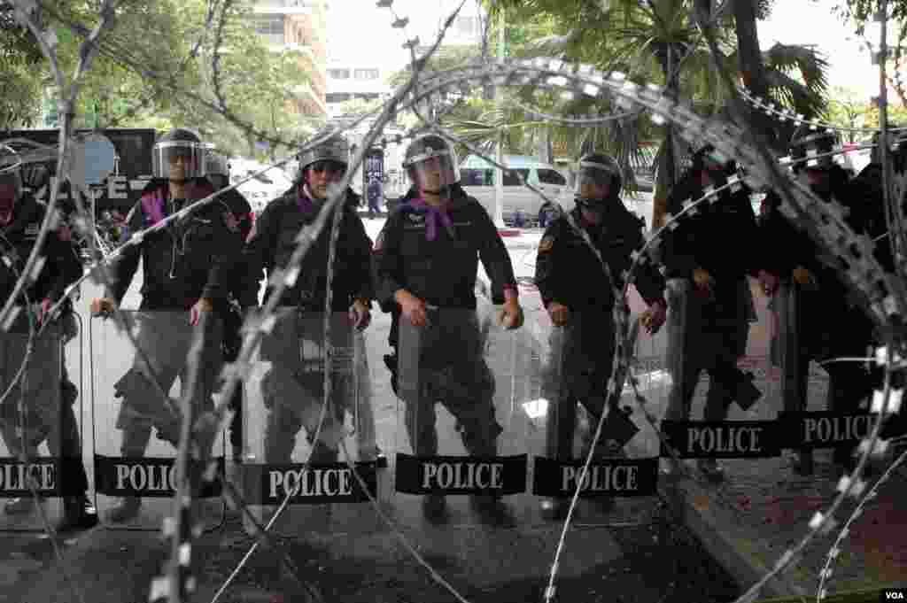 Polisi di belakang kawat berduri di markas mereka di Bangkok. (VOA/Steve Herman)