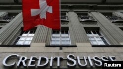 The logo of Swiss bank Credit Suisse is seen below the Swiss flag at a building in the Federal Square in Bern, Switzerland, May 15, 2014. 