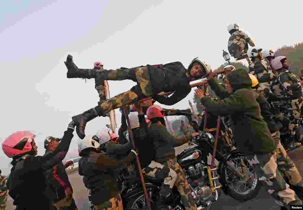 India&#39;s Border Security Force (BSF) &quot;Daredevils&quot; women motorcycle riders help their colleague to balance on a bike during a rehearsal for the Republic Day parade on a cold winter morning in New Delhi.