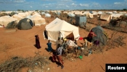 FILE - Refugees stand outside their tent at the Dadaab camp near the Kenya-Somalia border, Oct. 19, 2011. The Dadaab camp has hosted hundreds of thousands of Somali refugees for decades.